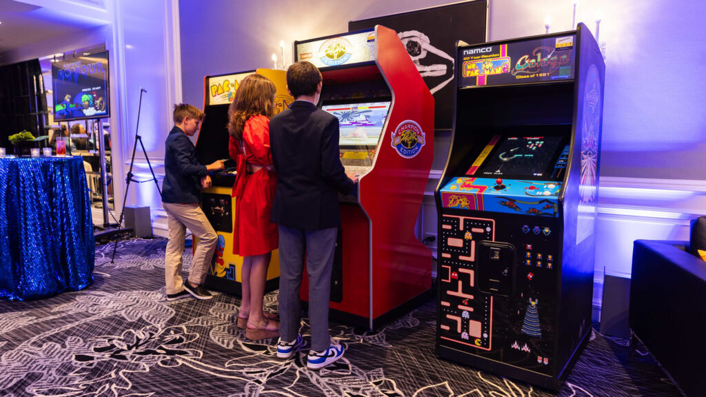 Kids playing Pac-Man, Street Fighter, and Galaga arcade machines, with Captain Novolin on a TV in the background.