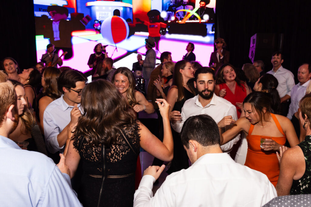 Gala attendees dancing with Breakthrough T1D One World dance party video playing in the background.