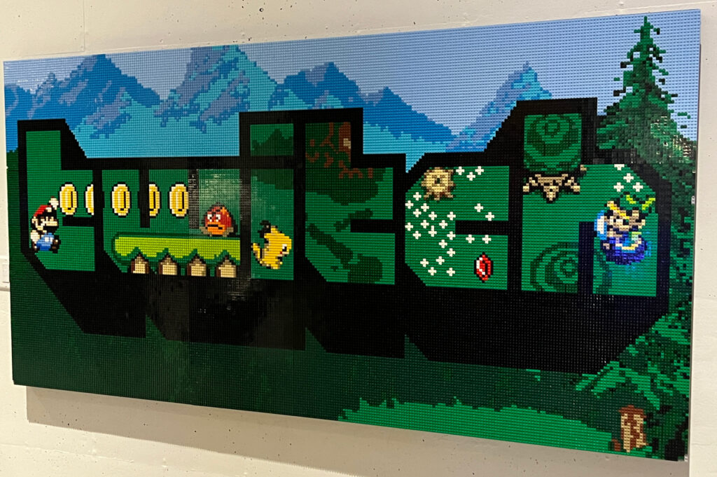 Lego art of a Twitch logo with SuperMario sprites in the letters and a mountain range in the background.