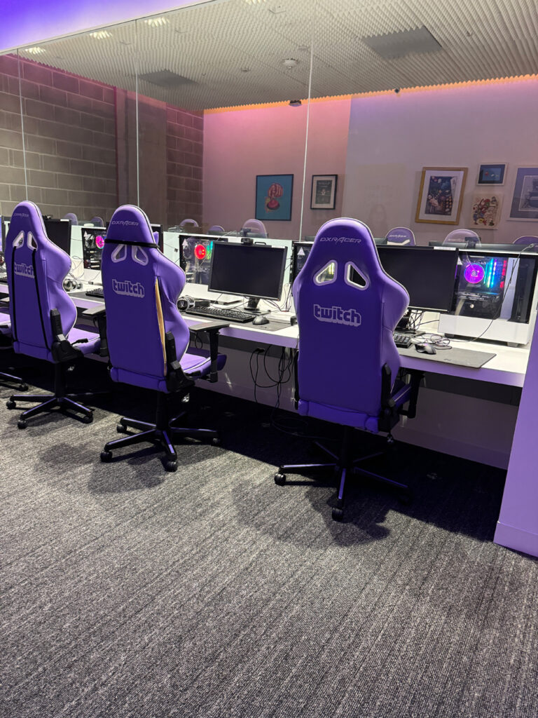 Purple gaming chairs with Twitch logos set up in front of computers decked out for streaming.