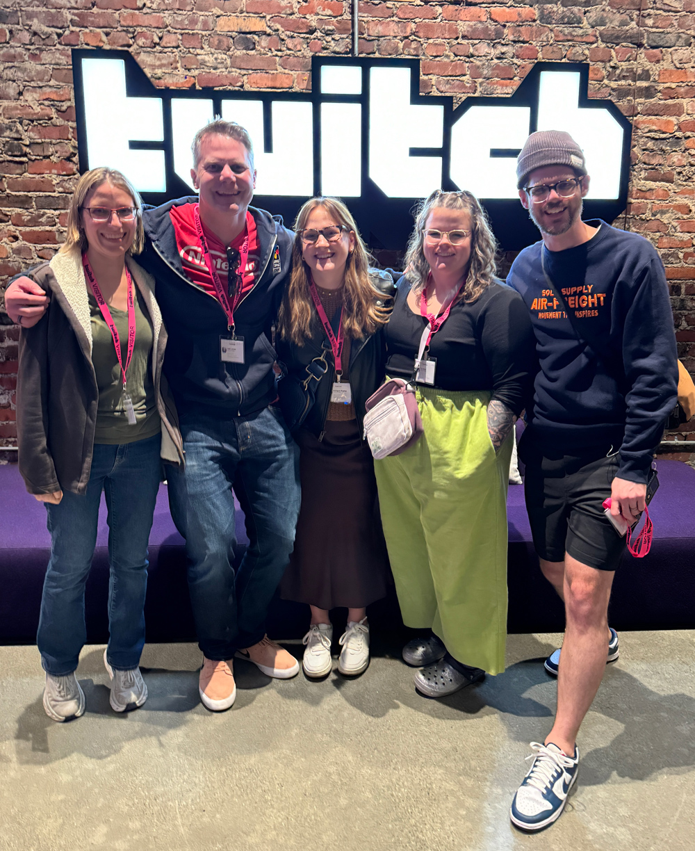 A group of people standing in front of the Twitch logo.